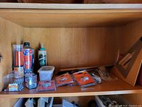 Top shelf containing screws, metal brackets, wood glue, and various small packaged hardware parts.