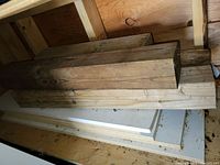 Wooden planks and beams stacked inside a bin; some dirt and signs of wear visible