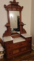 Full front view showing dresser base with marble tops, drawers and attached mirror