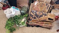 Rugs folded and stacked showing geometric tribal patterns, faux greenery vines placed next to hanging light fixture chain and components.