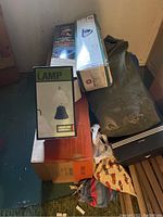 Photo showing boxed tents and green tent bag on floor near wall.