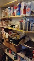 Photo showing shelves with various cleaning sprays, metal cans, boxes containing hardware and miscellaneous items