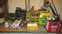 Wide shot of multiple hardware organizers, broom, dustpan, cords and miscellaneous items on wooden pallets and a plastic crate