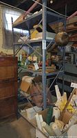 Two matching metal shelving units filled with various household items, located in a cluttered basement environment.