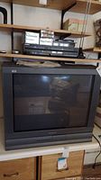 Front view of Panasonic 27-inch CRT television with Sony VHS/DVD player and digital converter box on top.