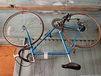 Blue Miyata men's bike suspended from garage ceiling hooks seen from side, showing complete frame, tires, and handlebars.