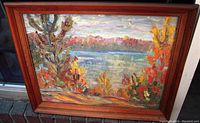 Full frontal photo of framed impressionist oil painting by Frank Arnott showing colorful autumn landscape with trees and water.