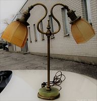 Twin arm table lamp with amber art glass shades and green marble base seen from front side in daylight