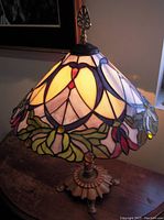 Front view of lit stained glass shade and decorative metal base