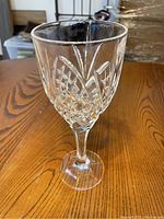 Close-up image showing the detailed cut glass pattern on a single crystal wine glass, highlighting the diamond and leaf shapes on the bowl.