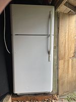 Closed view of full size white refrigerator with freezer on top, showing two doors and handles.