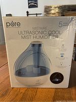 Front view of the Pure MistAire Ultrasonic Cool Mist Humidifier in its unopened retail box showing model image and branding.