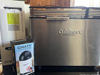 Cuisinart bread maker with control panel, baking pan inside and Gourmet Cheese Grater box alongside it
