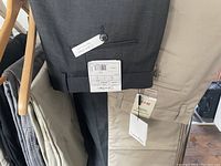 Close-up view of beige and dark gray Calvin Klein pants with tags showing size and brand details