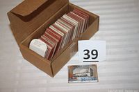 Cardboard box containing approximately 108 paper-mounted color slides and original promotional folder of mini prints