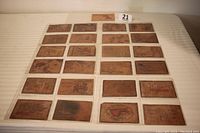 Full view of 24 leather postcards arranged in rows on a white surface.