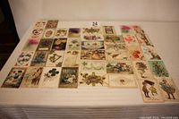 Overview of the full collection of 42 early 1900s postcards laid out flat on a white surface showing various colors, designs, and sizes around 3.5x5.5 inches