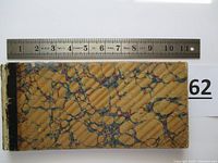 Top view of front marbled cover of certificate booklet with a ruler for scale.