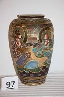 Full view of the enamel Asian vase showing the painted and gilded designs with five men portrayed around the body.