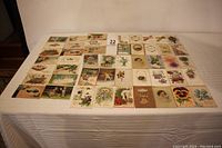 Overhead view of all 48 antique birthday postcards arranged in rows on a white surface