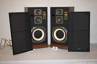 Front view of two Fisher speakers with grilles removed showing driver configuration and labels.