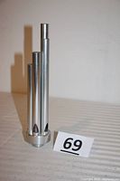 Front view showing five vertically aligned aluminum tubes of different lengths on a circular base.