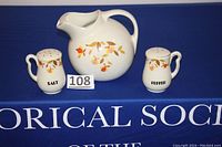 Photo showing full set of Hall China Jewel Tea Autumn Leaf salt, pepper shakers and ice lip ball jug, all with autumn leaf motifs on white porcelain.