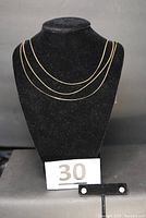 Front view on velvet bust showing three necklaces draped and two stud earrings on display stand