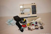 Kenmore sewing machine with foot pedal, owner's manual, and sewing accessories including pincushion, measuring tape, needles, threads, and more