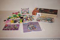 Overview of lot showing Lego Friends set pieces in various pastel colors and partially assembled, alongside original instruction manuals and the Lego Building Toy 001 Gears set box.