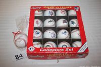 Red collector's box containing 16 Rawlings American League replica baseballs in compartments, plus an additional wrapped Rawlings official baseball to the side.