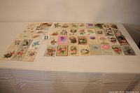 Full layout showing 48 different antique birthday postcards arranged on table, illustrating variety of floral and festive designs typical of early 1900s.