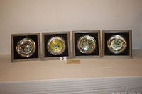 All four framed plates displayed side by side on table