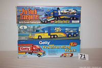 Photo of the three toy trucks stacked in original boxes showing the front and top of the packaging with colorful branding and product details.