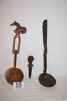 Photo showing all three items: giraffe ladle with broken lower part, alligator ladle, and carved bottle stopper