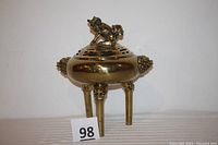 Full view of the large brass incense burner showing its three legs and cut-out patterns on the body.