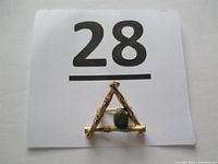 Photo of vintage Wells sterling silver and gilt triangular bamboo brooch with a central green jade stone on a white background with lot number 28 card.