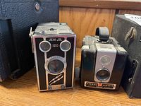 Front view of Jem Jr. 120 box camera and Brownie Hawkeye camera showing camera faces and lens details.
