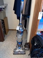 Full front view of Hoover Air Cordless upright vacuum cleaner showing its design, handle, dust container labelled 'Air Cordless','WindTunnel' suction and blue accents.