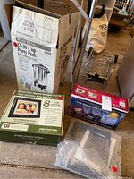 Photo of West Bend party percolator box along with three digital photo frames; two boxed, one unboxed in bubble wrap.
