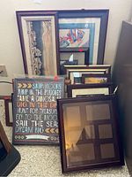 Group of assorted empty frames and framed prints, including a motivational quote and a colorful fish print, along with various frame sizes and styles