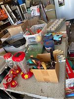 Table with multiple bird feeders and garden tools arranged, showing various supplies available in the lot.