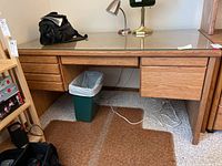 Full front view of oak desk with glass topper, showing drawer layout and desk surface condition.