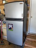 Full view of two-door refrigerator/freezer on caster wheels in garage