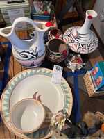 Overview photo of entire ceramic set including large plate, bowl, jugs, and smaller vessels on wooden table.