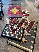 All six Southwest style flat weave rugs on carpet, fanned out