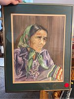 Close-up photo of the framed portrait of an older woman wearing a green headscarf and detailed clothing with jewelry.