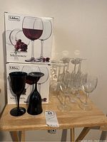 20 stemmed wine glasses with clear and dark colors, with two stacked Libbey Midtown boxes in background