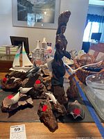 Overview photo showing the set of eight wood and resin sculptures featuring birds and standing figure on a table along with other household items.