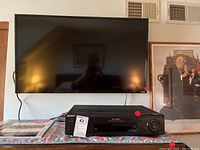 Photo showing a 40-inch Vizio flat screen TV mounted on the wall above a Sony VHS VCR unit on a table.